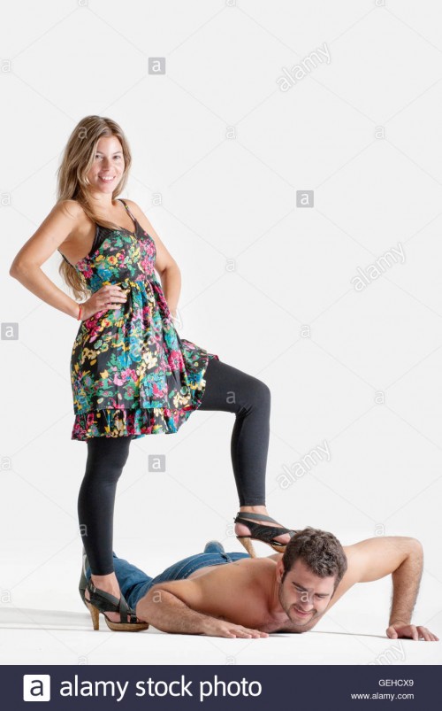 woman-with-one-foot-on-the-back-of-a-man-in-the-floor-in-a-dominant-GEHCX9.jpg